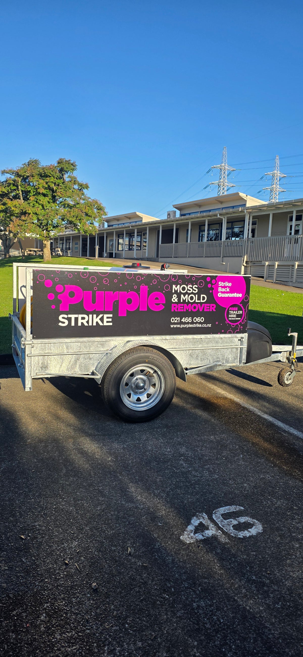 The Purple Strike moss and mould treatment trailer parked in a school car park, with the school buildings and field behind it